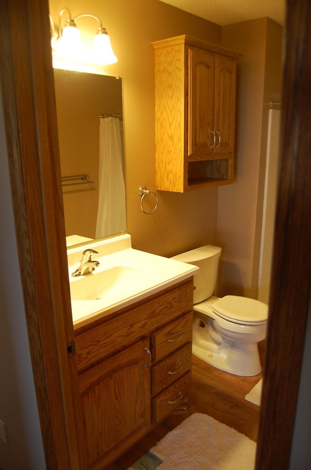 bathroom featuring vanity, a shower with shower curtain, toilet, and wood finished floors