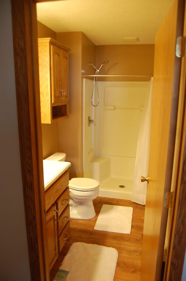 full bath with curtained shower, toilet, wood finished floors, and vanity