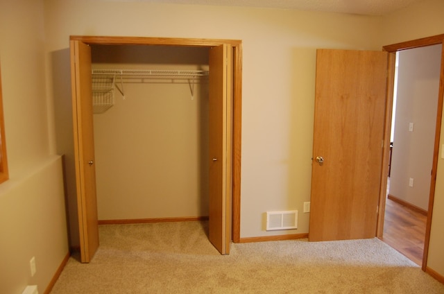 unfurnished bedroom with baseboards, visible vents, carpet floors, and a closet