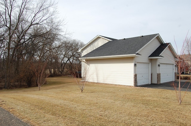 view of side of property with a yard, a garage, and a shingled roof