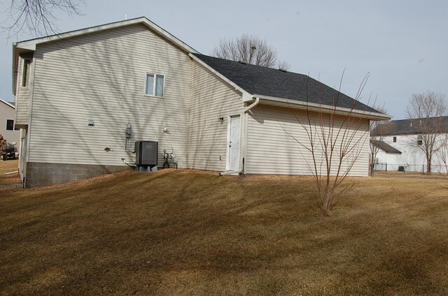 view of home's exterior with central air condition unit, a lawn, and a shingled roof