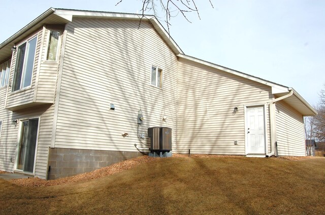 view of side of home with central air condition unit and a lawn