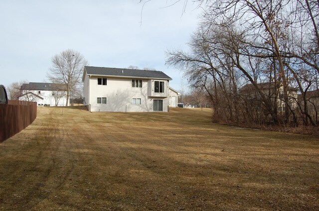 back of house featuring a lawn and fence