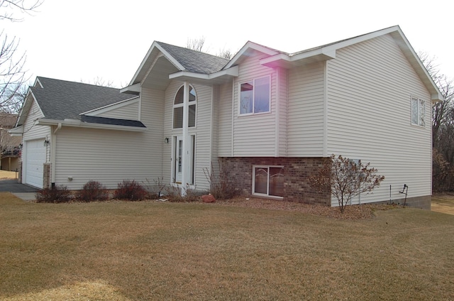 view of front facade featuring a front yard, an attached garage, brick siding, and a shingled roof