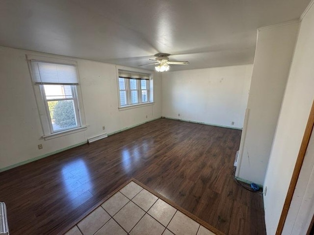 spare room featuring ceiling fan, a baseboard radiator, baseboards, and wood finished floors