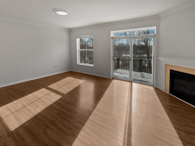 unfurnished living room with a fireplace, crown molding, baseboards, and wood finished floors
