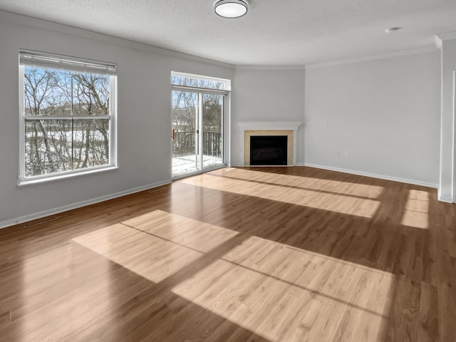 unfurnished living room with visible vents, baseboards, ornamental molding, a fireplace, and wood finished floors