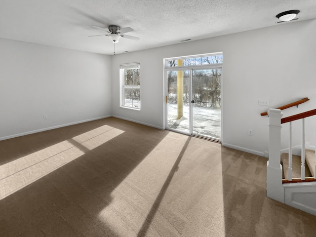 empty room with carpet, baseboards, stairs, a textured ceiling, and a ceiling fan