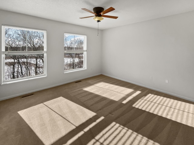 carpeted empty room featuring visible vents, ceiling fan, and baseboards