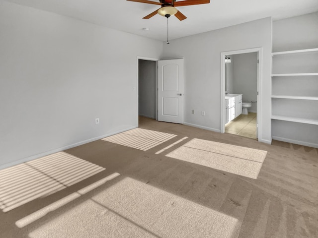 unfurnished bedroom with ensuite bath, a ceiling fan, baseboards, and carpet floors