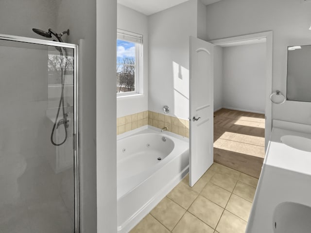 bathroom featuring tile patterned flooring, a tub with jets, a stall shower, and vanity