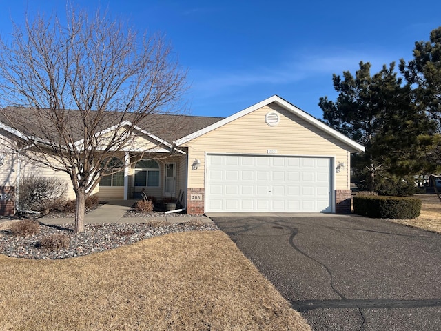 single story home featuring a garage, brick siding, and driveway