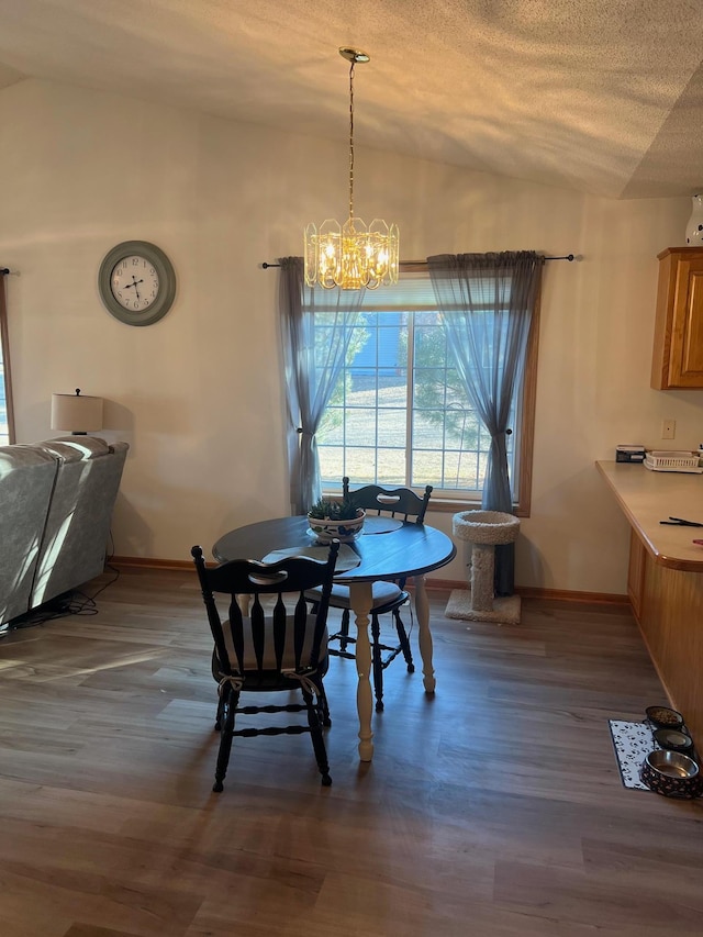 dining room featuring an inviting chandelier, wood finished floors, baseboards, and a textured ceiling