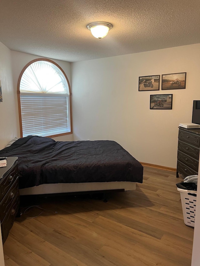 bedroom featuring wood finished floors and a textured ceiling