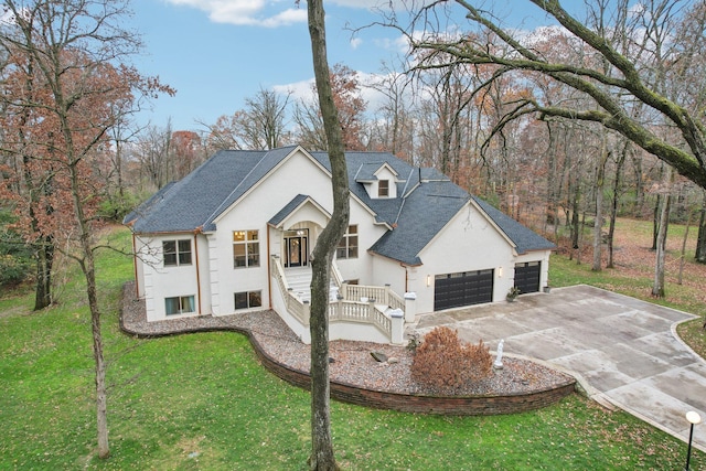 view of front of house with stucco siding, driveway, a shingled roof, a front yard, and an attached garage