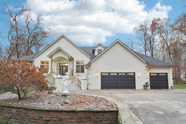 view of front of house with stucco siding, a garage, roof with shingles, and driveway