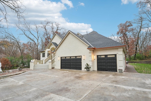 view of property exterior featuring a garage, a shingled roof, concrete driveway, and stucco siding