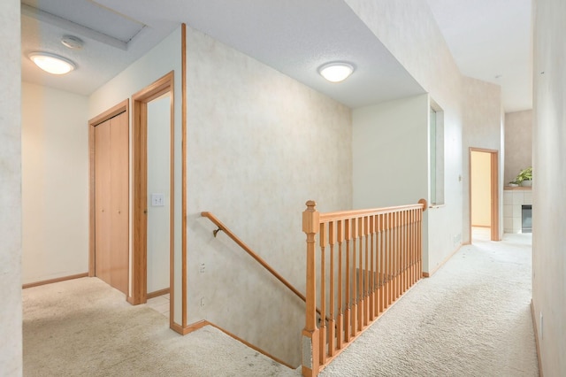 corridor featuring baseboards, an upstairs landing, and carpet flooring