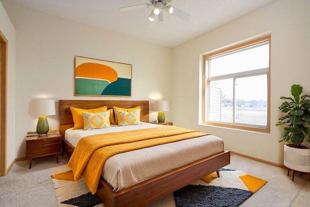 bedroom featuring baseboards, light colored carpet, and a ceiling fan