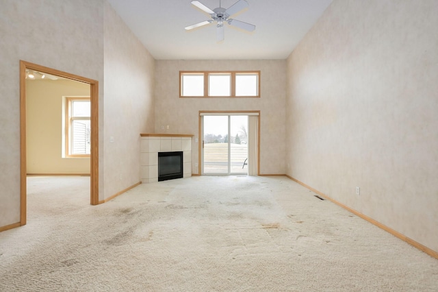 unfurnished living room with baseboards, carpet floors, a high ceiling, and a fireplace