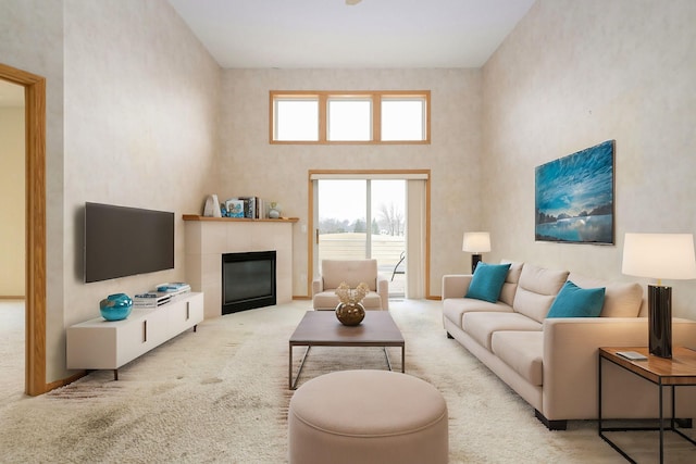 living area with a fireplace, a towering ceiling, and carpet floors