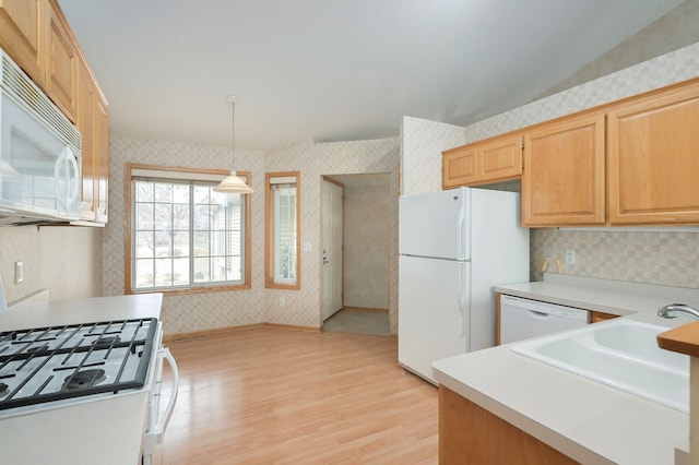 kitchen with white appliances, wallpapered walls, light wood-type flooring, and a sink