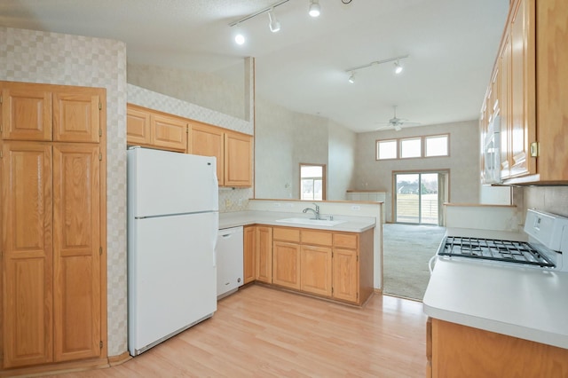 kitchen with a sink, white appliances, a peninsula, light countertops, and ceiling fan