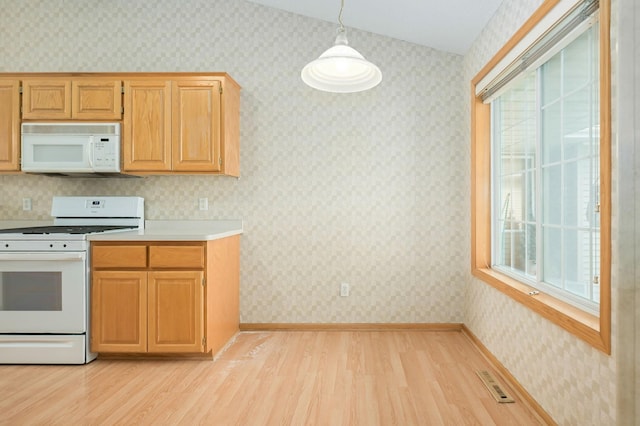 kitchen with light wood finished floors, visible vents, white appliances, and wallpapered walls