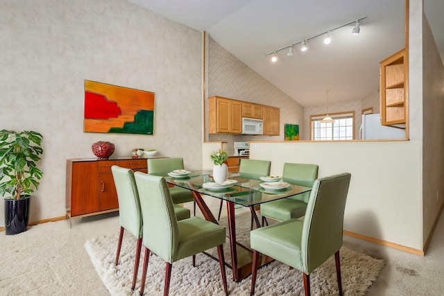 dining room featuring track lighting, wallpapered walls, baseboards, light colored carpet, and high vaulted ceiling