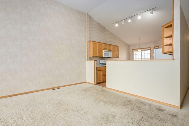 interior space with white appliances, wallpapered walls, track lighting, vaulted ceiling, and light carpet