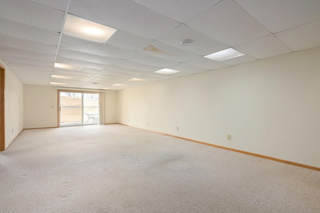 spare room featuring light colored carpet, baseboards, and a drop ceiling