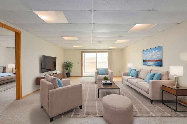 carpeted living room featuring baseboards and a paneled ceiling