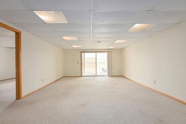 spare room with light colored carpet, baseboards, and a drop ceiling