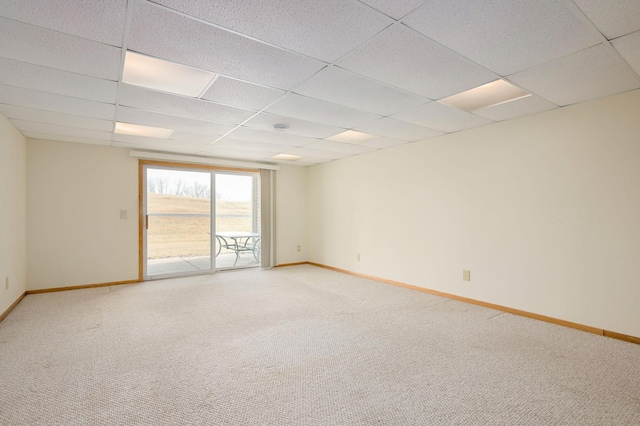 unfurnished room featuring a drop ceiling, baseboards, and light colored carpet