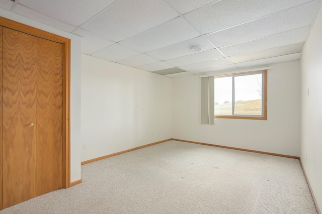 unfurnished room featuring a paneled ceiling, baseboards, and carpet flooring