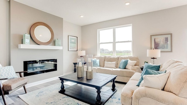 living area with a glass covered fireplace, light wood-style flooring, recessed lighting, and baseboards