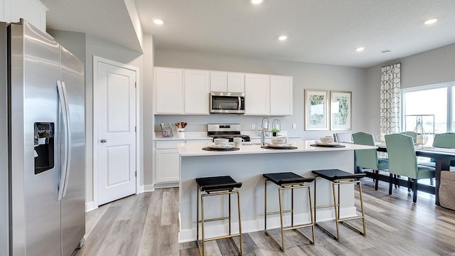 kitchen with light wood finished floors, light countertops, recessed lighting, appliances with stainless steel finishes, and white cabinets