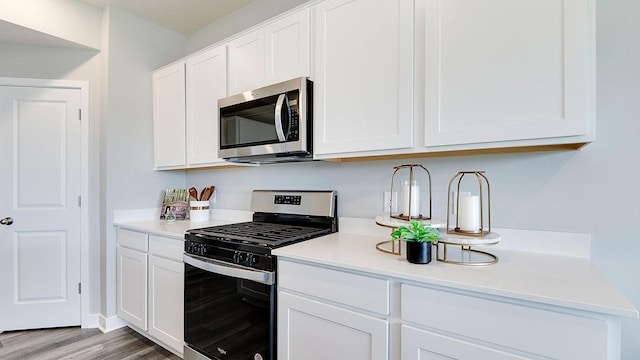 kitchen with white cabinets, stainless steel appliances, light countertops, and light wood-style floors