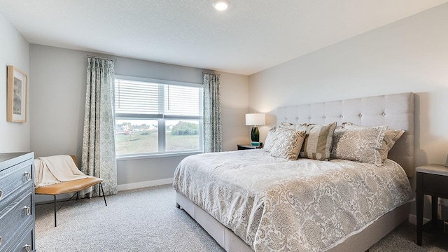 carpeted bedroom featuring a textured ceiling and baseboards