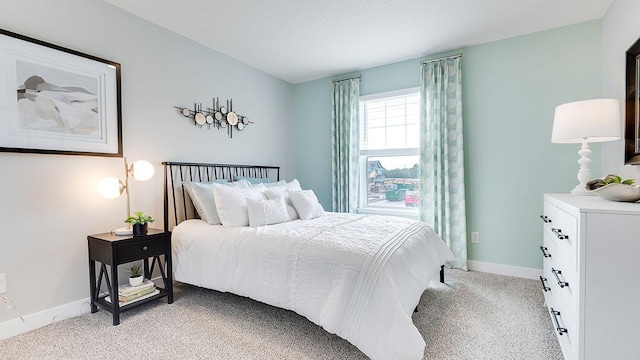 bedroom with baseboards and light colored carpet