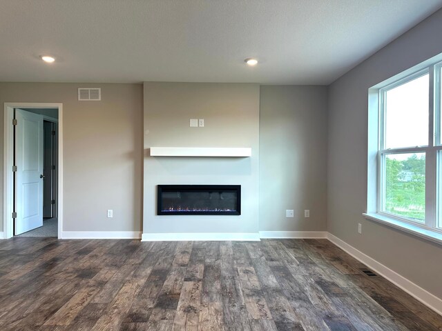 7856 Martin Ave NE, Otsego, MN 55330 - unfurnished living room featuring wood finished floors, baseboards, a glass covered fireplace, recessed lighting, and a textured ceiling