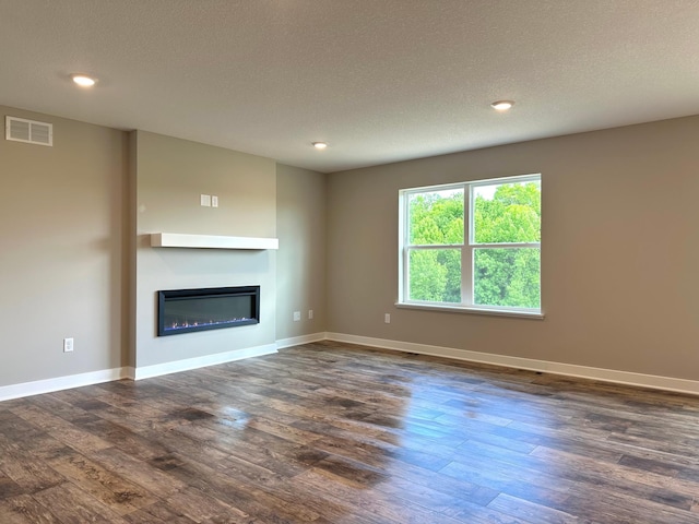 7856 Martin Ave NE, Otsego, MN 55330 - unfurnished living room with a glass covered fireplace, dark wood-style flooring, a textured ceiling, baseboards, and recessed lighting