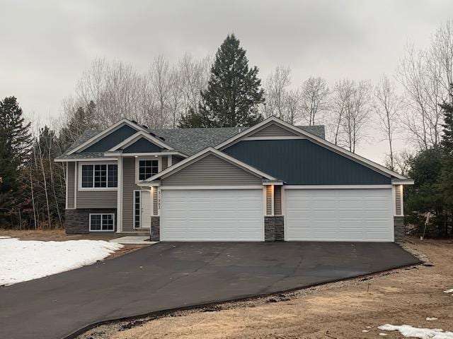 view of front of property featuring aphalt driveway, stone siding, central AC unit, and a garage