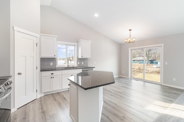 kitchen featuring a chandelier, light wood-style flooring, electric stove, white cabinetry, and a sink