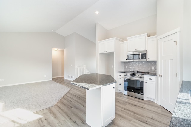 kitchen featuring lofted ceiling, decorative backsplash, light wood-style flooring, appliances with stainless steel finishes, and white cabinetry