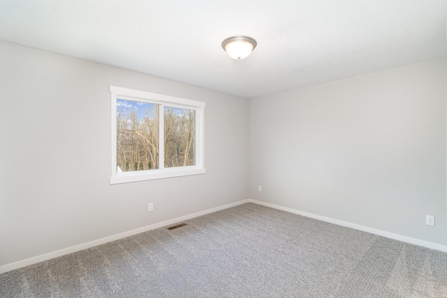 carpeted spare room featuring visible vents and baseboards