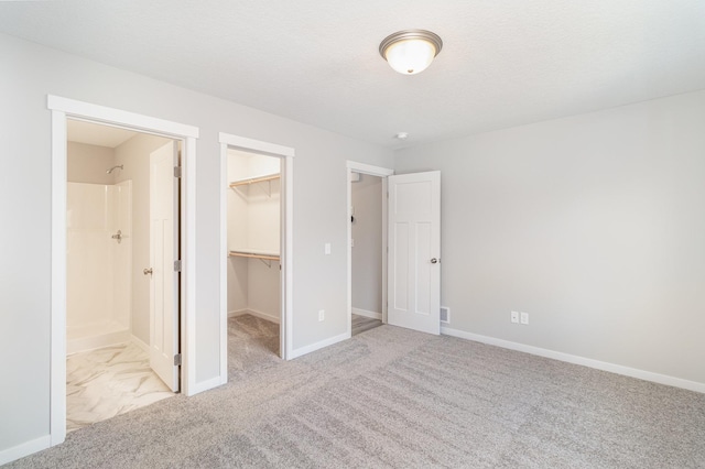 unfurnished bedroom with a spacious closet, carpet flooring, a closet, and baseboards