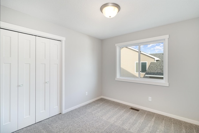 unfurnished bedroom featuring carpet flooring, baseboards, visible vents, and a closet