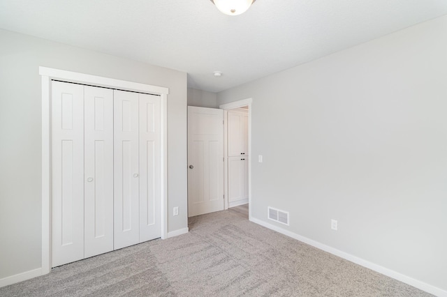 unfurnished bedroom with a closet, visible vents, carpet flooring, and baseboards