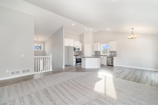 unfurnished living room featuring an inviting chandelier, recessed lighting, light wood finished floors, and high vaulted ceiling